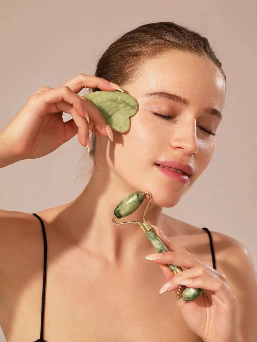 Mujer usando la gua sha en la cara y el roller en el cuello