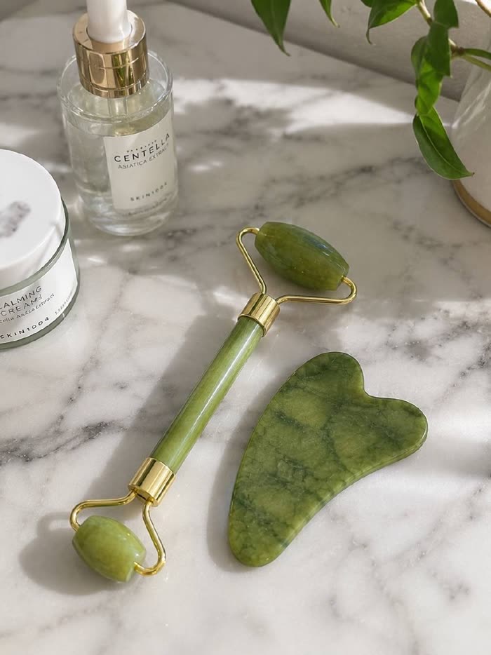 Roller de jade y gua sha en el baño junto a los sérums de una clienta