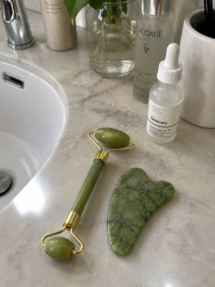 Set de jade en la encimera del baño con sérums Caudalie y The Ordinary